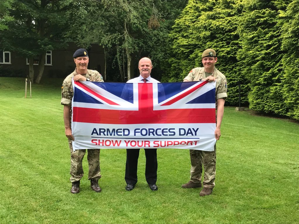 Reservist, Veteran and Cadet Instructor holding Armed Forces Day flag