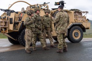 Unit member being briefed next to a Jackal 2 vehicle