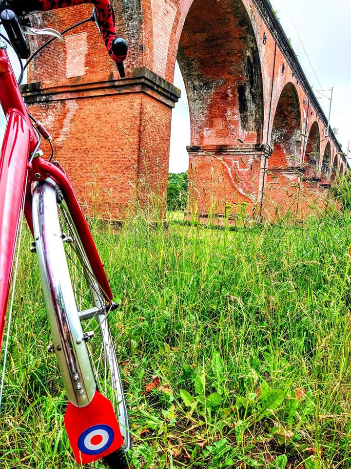 The front wheel of a bike displaying a Royal Air Force logo is propped up in front of an aquaduct