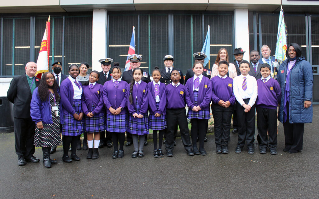 Students and staff at King Solomon International Business School pose smiling for the camera with representatives from WAWI, West Midland RFCA, Royal Navy and Standard Bearers