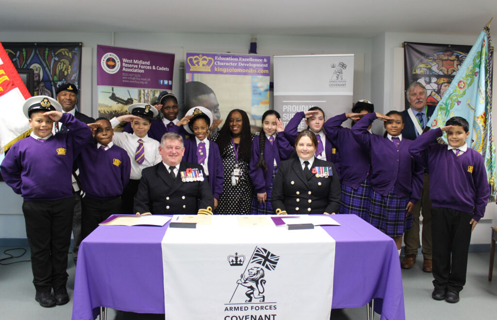 Students and staff salute alongside members of the Royal Navy