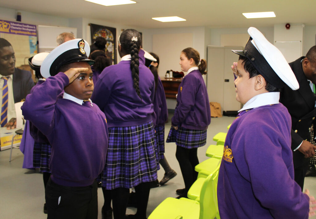 Students demonstrate their salutes whilst trying on the Navy's uniform hats