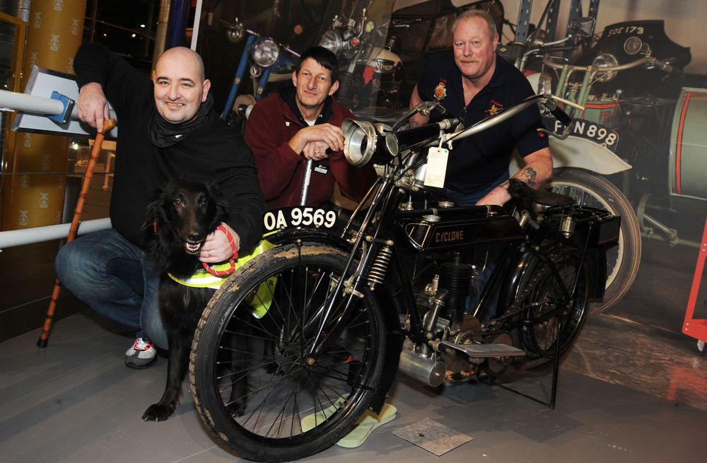 Wayne, Tim and David crouch by the 1914 Cyclone bike they are restoring as part of the Volunteering For Veterans Scheme