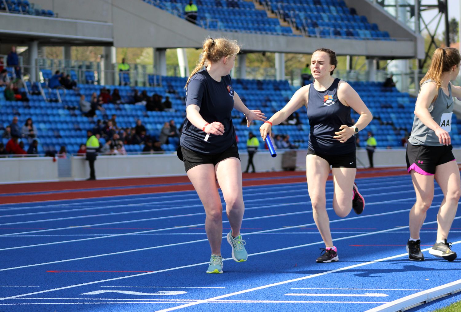 Two team members from BUOTC pass the relay baton to each other mid-race at the Midlands Army Athletics Championships