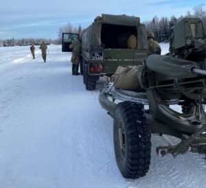 Unit members by their military vehicles in a snowy climate.