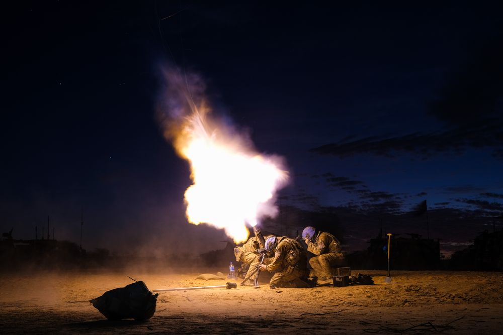 The winning photo called 'Light Them Up' features three soldiers firing a large gun in the dark, with a burst of light firing out of the end and lighting up the area around them