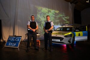 RAF Police officers stood by a police car.