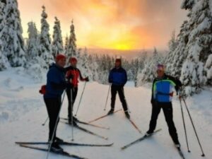 Team members skiing at sunset.