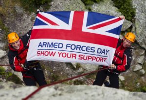 Two climbers holding an Armed Forces Day flag.