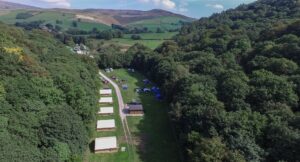 Hayfield campsite aerial view. Surrounded by woodlands and hills.