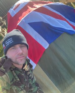 Graham next to his tent, with Union Jack flag draped on top.