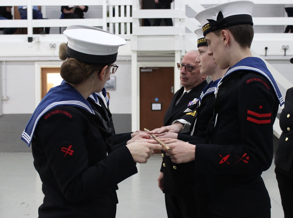 The Sea Cadets are stood, working as a team to lower a bamboo cane gently to the ground, each only using one finger per hand, to practise working together as a team. CFAV is on hand to support.