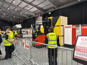 A fork lift truck driver attempting the tricky course, with judge looking on.