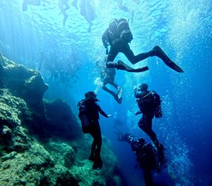 Cadets and adult volunteers in diving kit underwater.