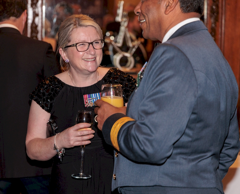 Deputy Chief Executive, Lesa, is smiling at a colleague, dressed in a black dress with miniature medals, pictured at our Defence Employer Recognition Scheme Gold Awards event in the Autumn.